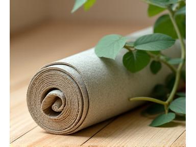 Sustainable natural rubber yoga mat rolled up on a soft wooden floor